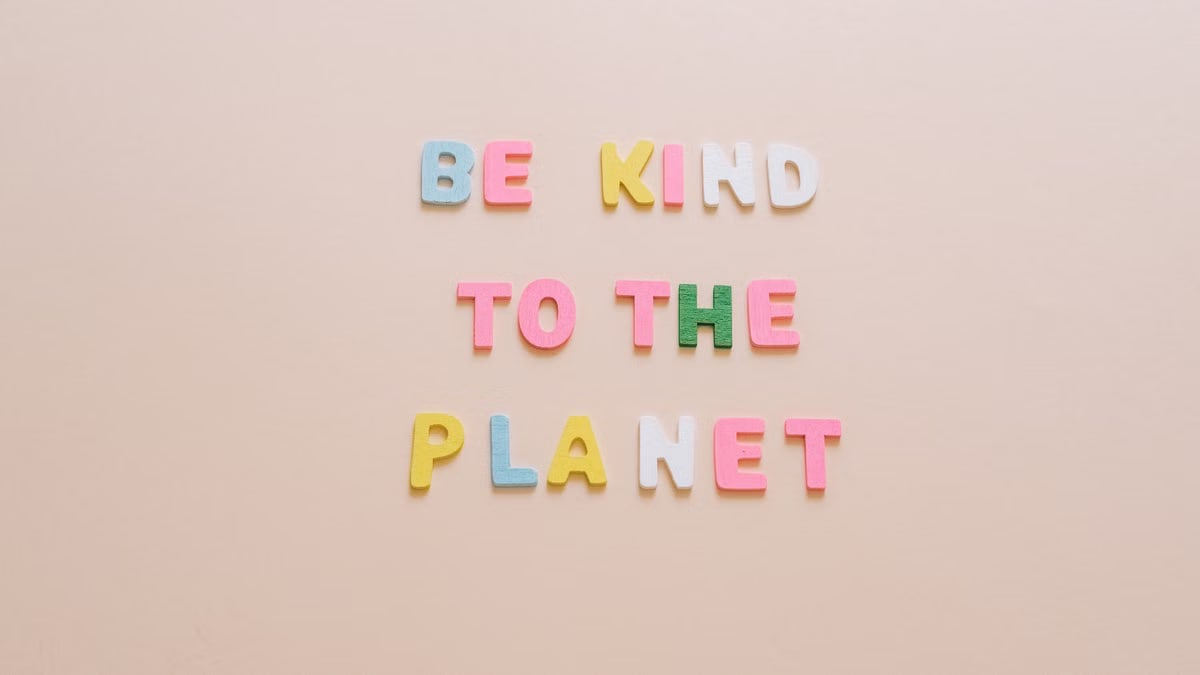 Colorful text advocating kindness to the planet against a minimalist beige backdrop.